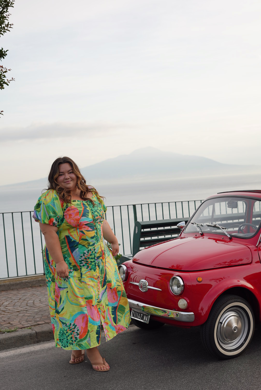 plus size fashion blogger Natalie in the City wears a Farm Rio dress from Anthropolgie nuuly plus size while standing next to a fiat in Sorrento Italy