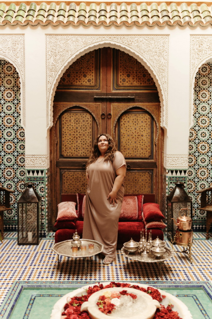 plus size fashion blogger Natalie in the City wears a caftan in Marrakech, Morocco while standing at the Riad Elegancia.