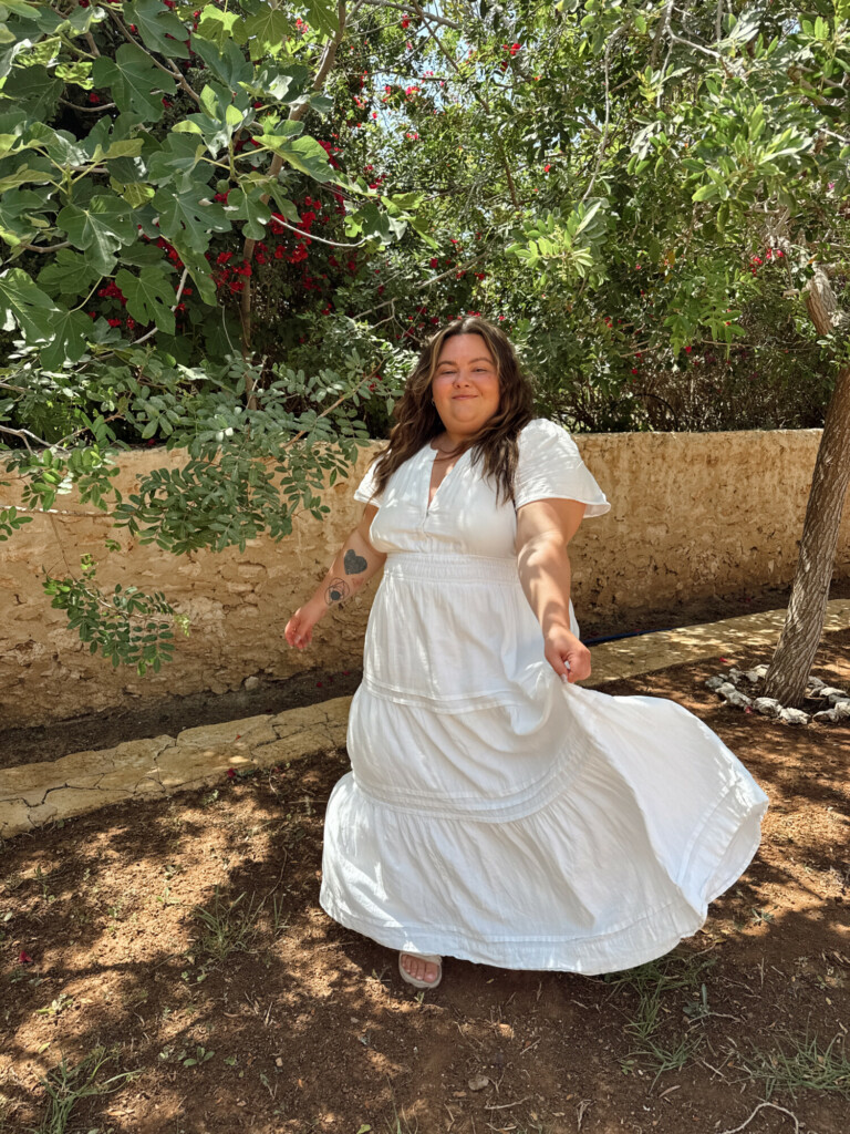 Plus size woman twirling in a white maxi dress in Morocco at a winery
